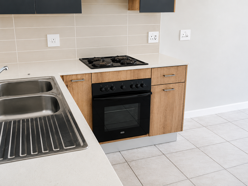 Modern kitchen featuring light wood cabinetry, stone countertops, a stainless steel double sink, and a built-in gas hob with oven.