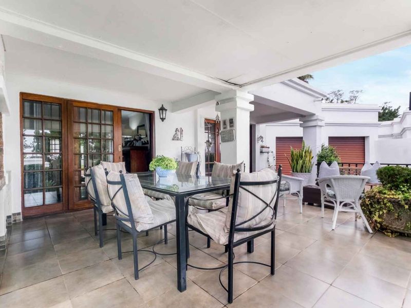 A spacious covered patio featuring tiled flooring and timber-framed glass doors, providing a seamless transition between indoor and outdoor living areas.