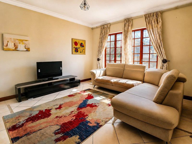 A comfortable living room featuring tiled flooring, classic wooden window frames, and decorative cove cornicing, providing a bright and functional space.