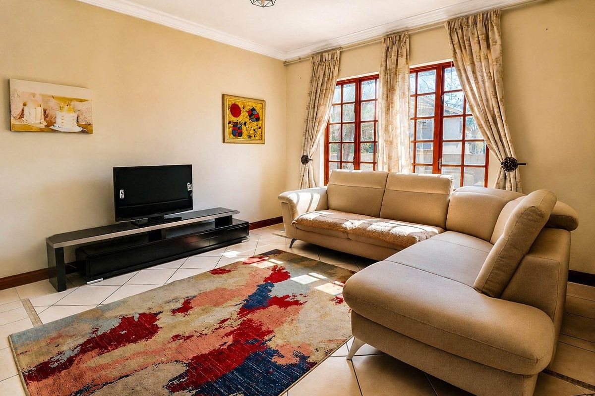 A comfortable living room featuring tiled flooring, classic wooden window frames, and decorative cove cornicing, providing a bright and functional space.