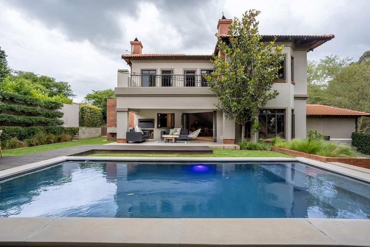 Rear view of the property featuring a swimming pool, wooden decking, covered patio area, and a balcony on the upper level.
