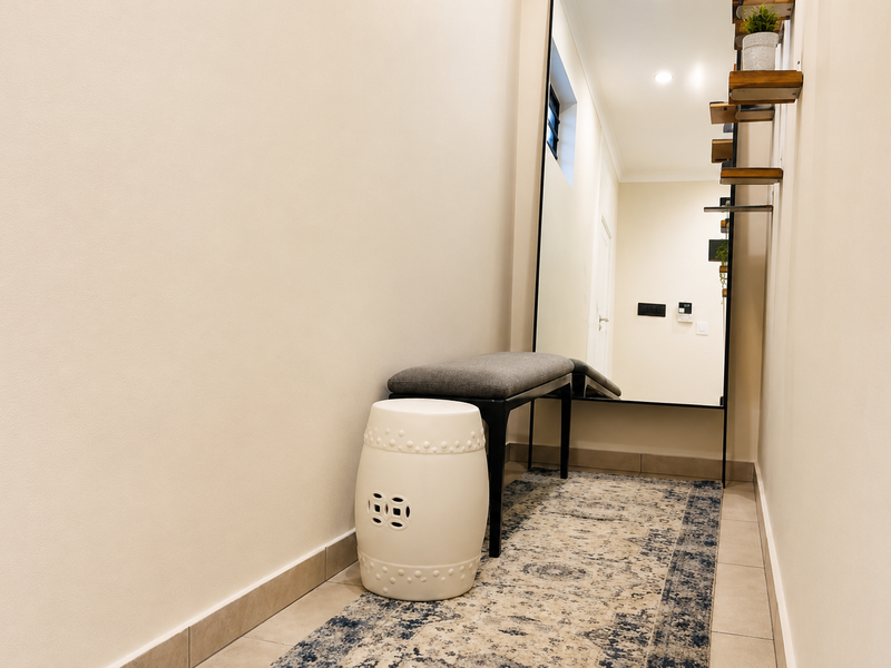 A clean and well-lit hallway featuring neutral tiled flooring and recessed ceiling lighting, creating a welcoming entrance space.