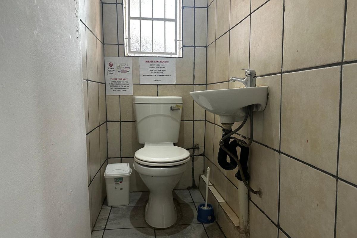 A compact guest bathroom featuring a standard toilet, wall-mounted basin, and tiled walls with a small window.