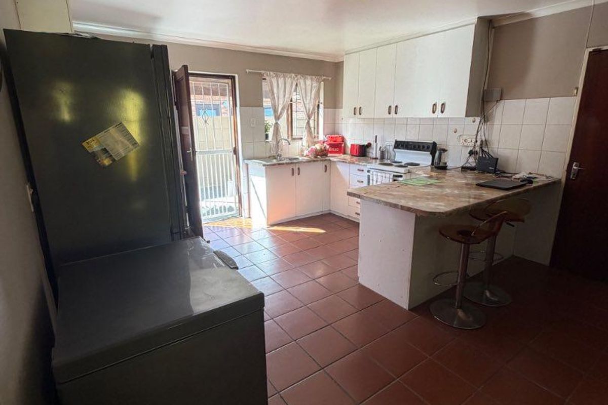 A functional kitchen featuring tiled flooring, built-in cabinetry, a breakfast bar, and a tiled backsplash, offering a practical layout for daily use.