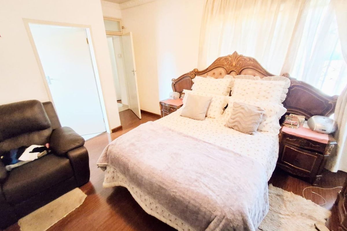 A bedroom featuring laminate flooring and decorative cornice detailing, providing a functional space with natural light from the window.