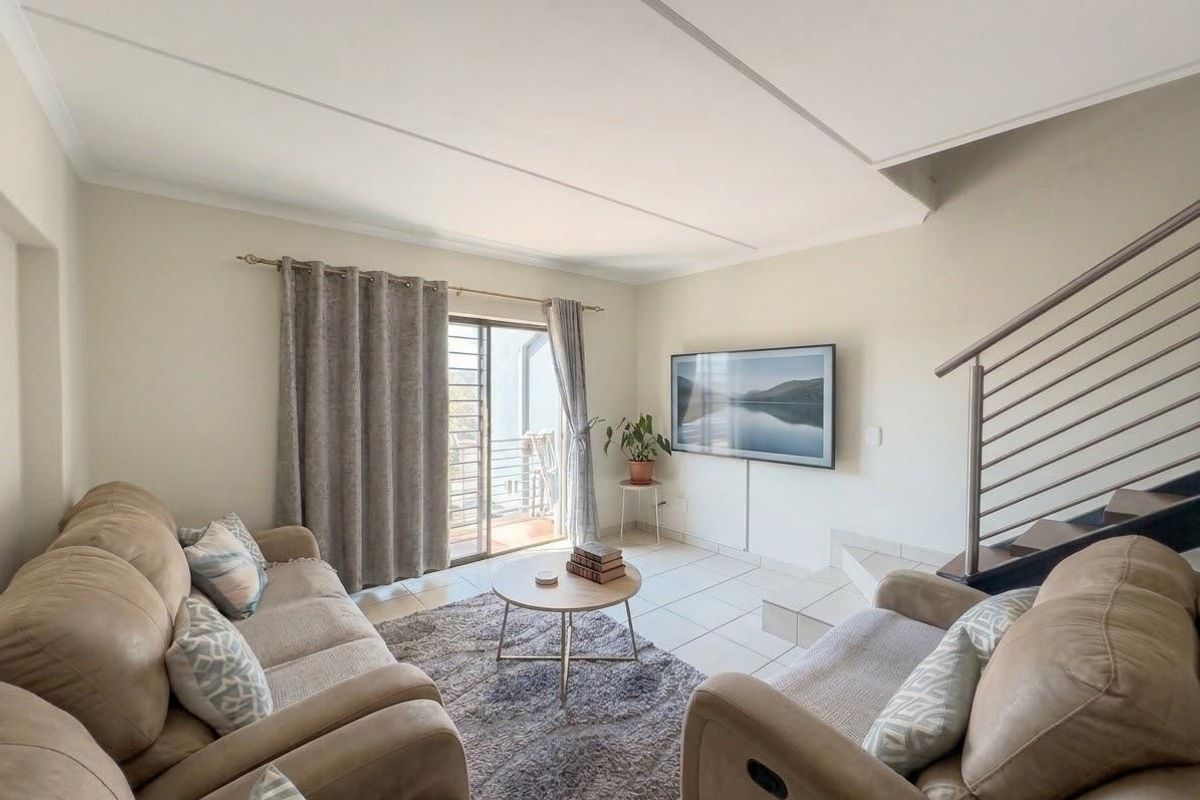 A bright living room featuring tiled flooring, a staircase with a modern metal railing, and a sliding glass door leading to an outdoor area.