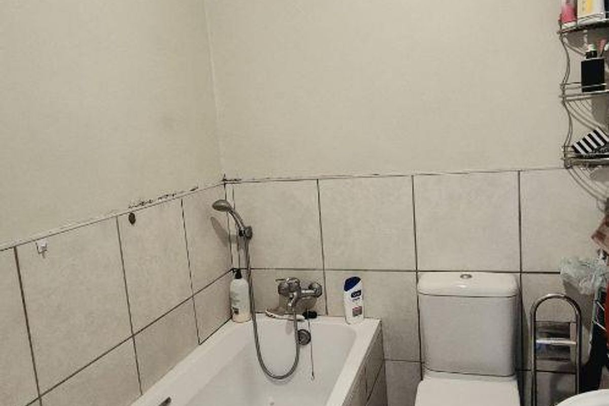 A functional bathroom featuring a bathtub with handheld shower, toilet, and pedestal basin, finished with ceramic tiling throughout.