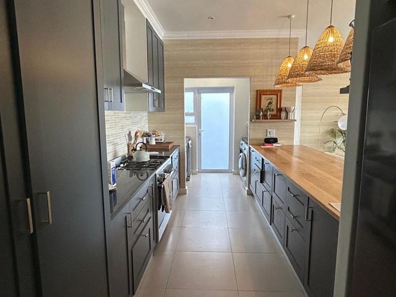 Modern galley-style kitchen featuring dark cabinetry, stone countertops, gas hob, and integrated appliances with a clean, contemporary finish.