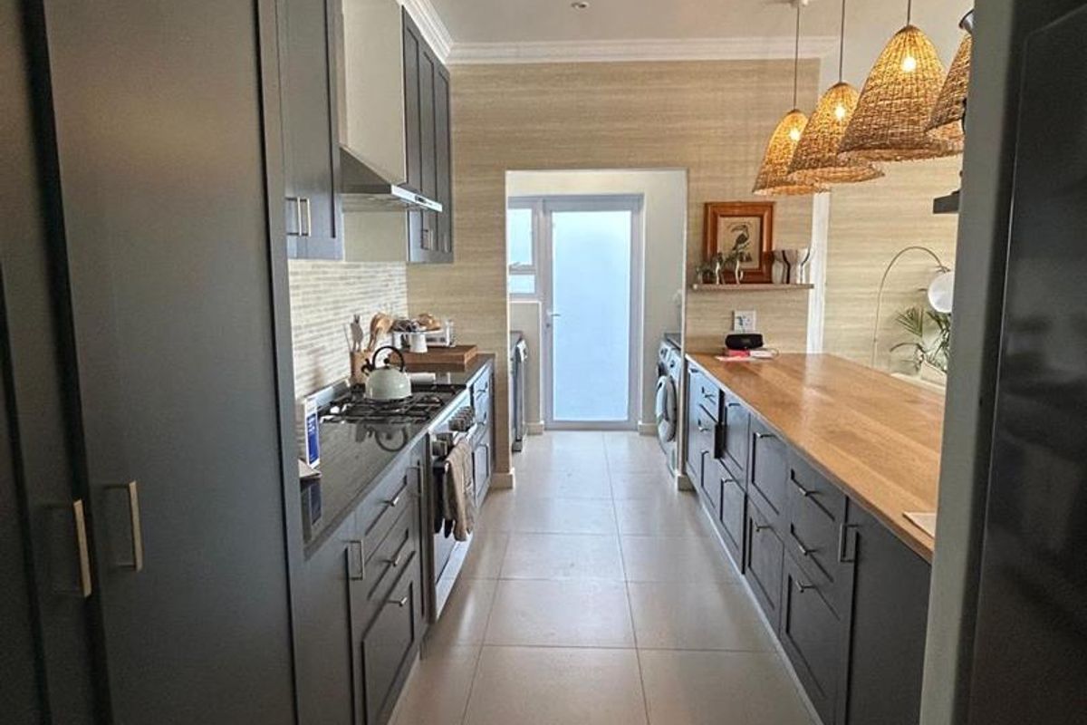 Modern galley-style kitchen featuring dark cabinetry, stone countertops, gas hob, and integrated appliances with a clean, contemporary finish.