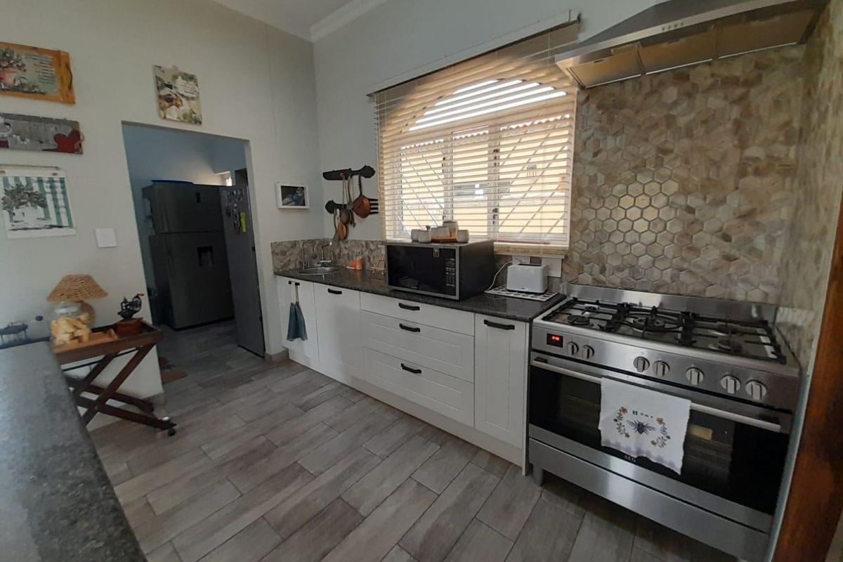 A functional kitchen featuring white cabinetry, a stainless steel gas stove with extractor fan, and a decorative hexagonal tiled backsplash.