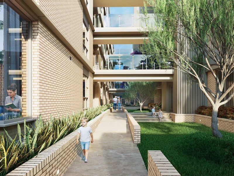 A modern residential complex featuring brick facade architecture, elevated glass-railed walkways, landscaped garden paths, and integrated outdoor lighting.
