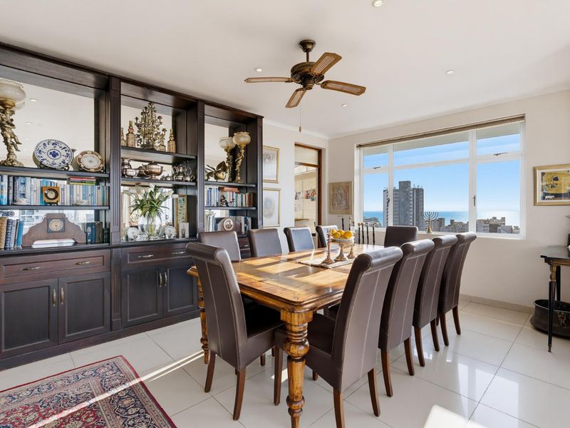 Spacious dining room featuring large windows with ocean views, tiled flooring, recessed lighting, and extensive built-in dark wood cabinetry.