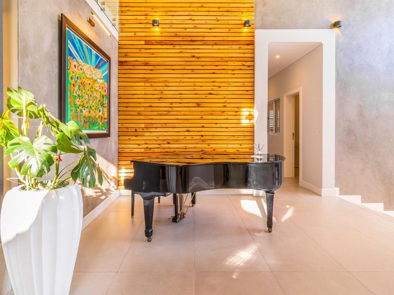 Elegant living area featuring a striking timber slat feature wall, polished tiled flooring, and modern recessed lighting with a glass balustrade staircase.