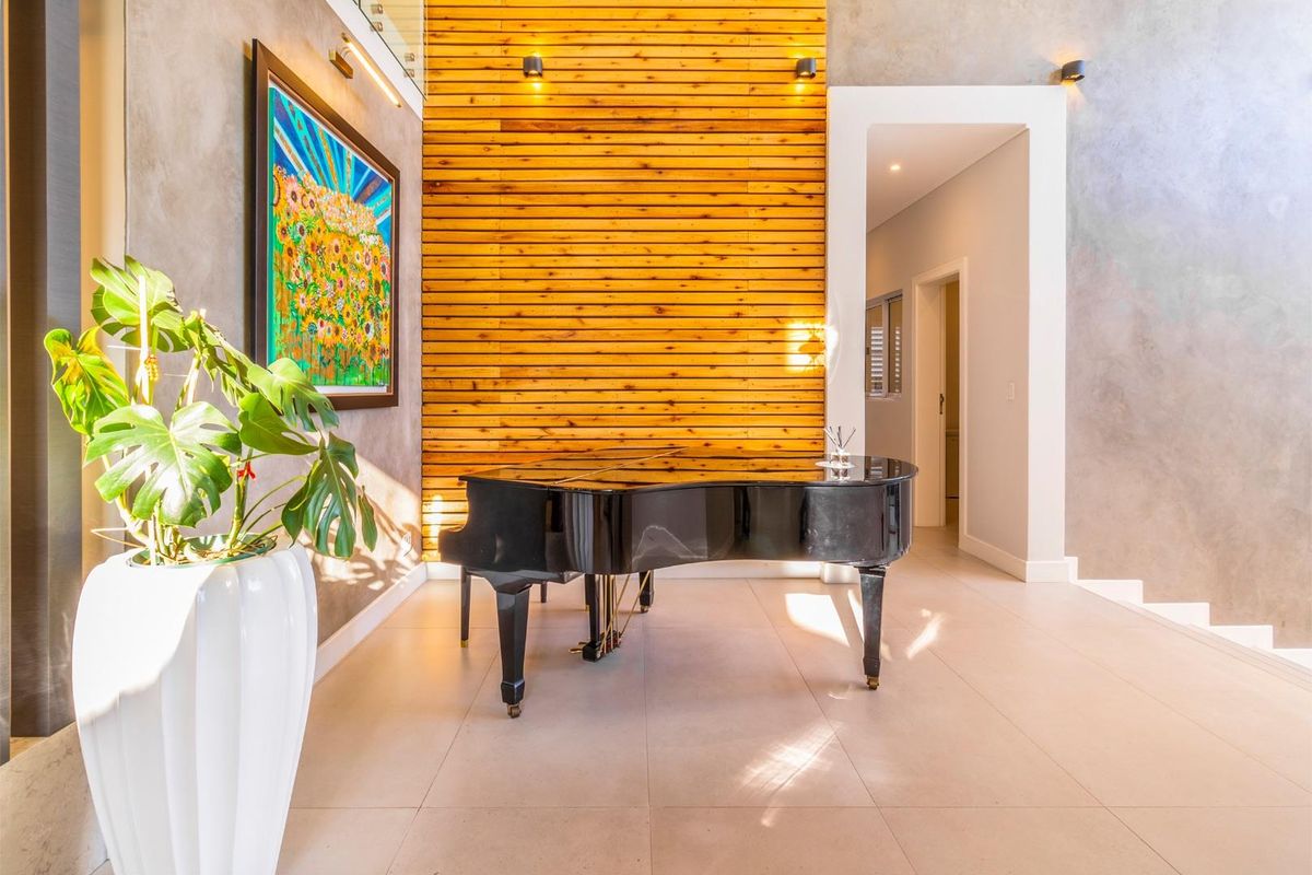 Elegant living area featuring a striking timber slat feature wall, polished tiled flooring, and modern recessed lighting with a glass balustrade staircase.