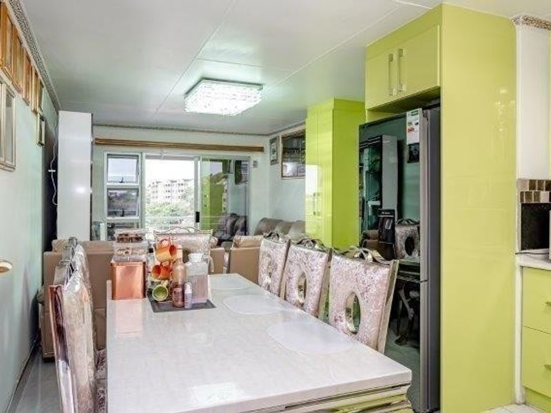Open-plan living and dining area featuring high-gloss lime green cabinetry, tiled flooring, and sliding glass doors leading to an outdoor space.