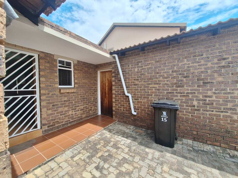 A private rear courtyard featuring face brick walls, a tiled patio area, and paved flooring, providing a functional outdoor space.