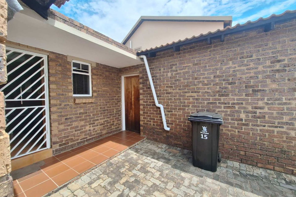 A private rear courtyard featuring face brick walls, a tiled patio area, and paved flooring, providing a functional outdoor space.