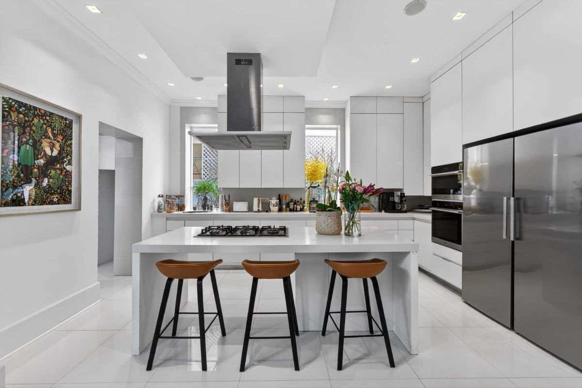 Modern, high-end kitchen featuring a central island with gas cooktop, sleek cabinetry, integrated appliances, and polished tiled flooring.