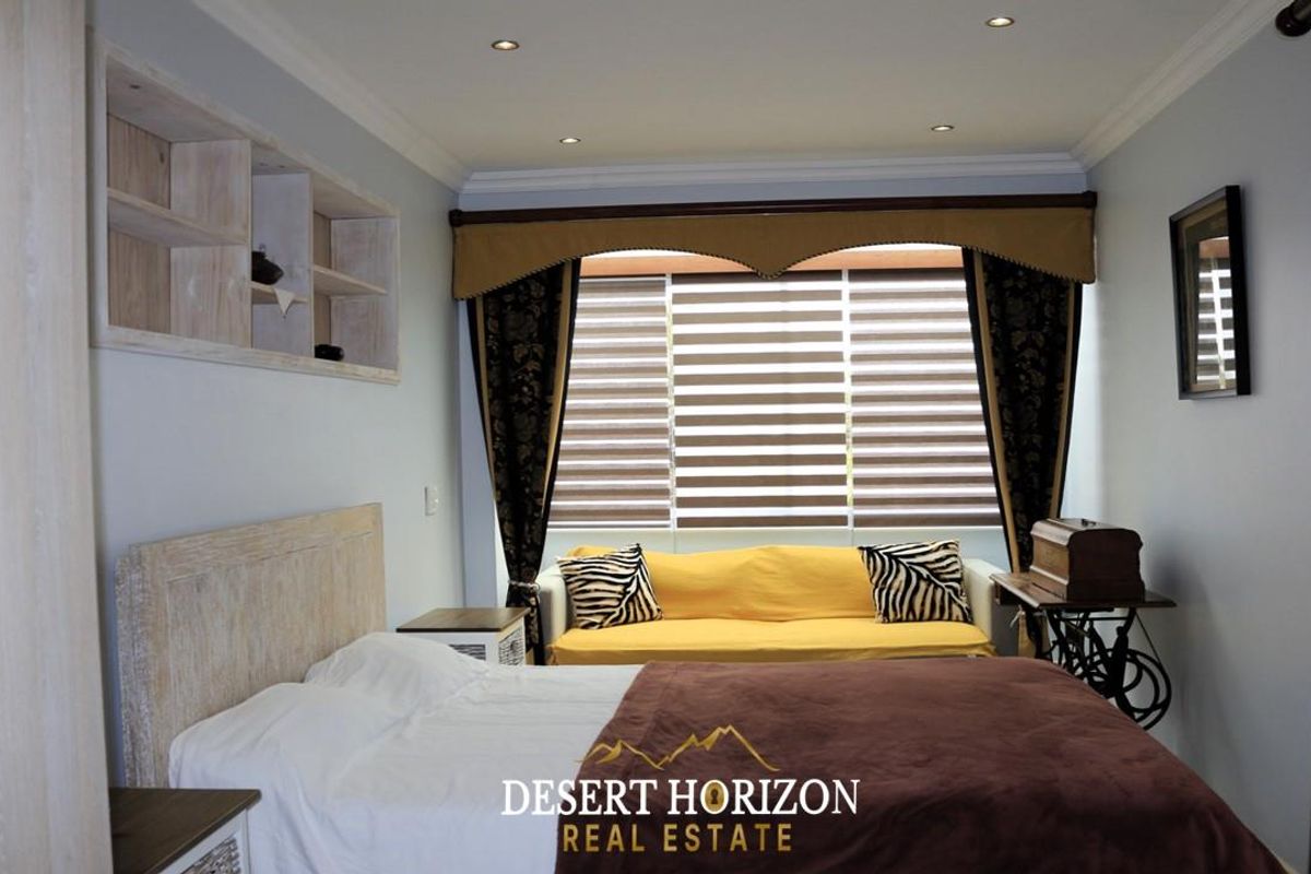A well-maintained bedroom featuring recessed downlighting, crown molding, and built-in wall shelving, providing a comfortable and functional living space.