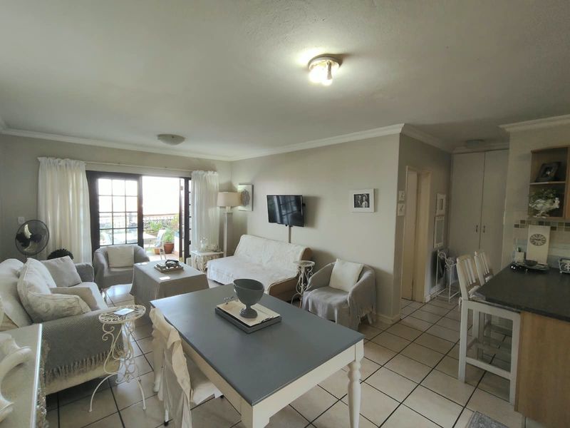 Open-plan living and dining area featuring tiled flooring, a breakfast bar, and sliding glass doors leading to an outdoor patio space.