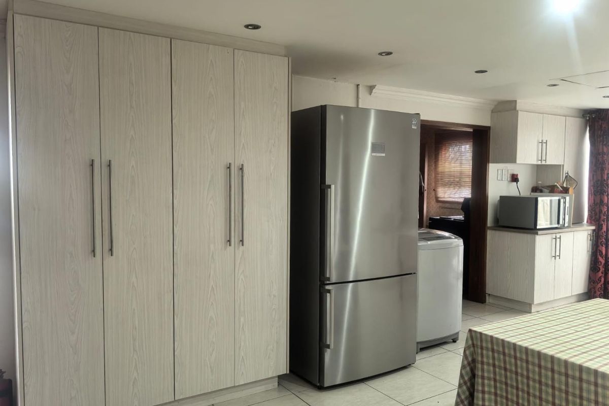 A functional kitchen area featuring light wood-grain built-in cabinetry, tiled flooring, and recessed ceiling lighting, providing ample storage and workspace.
