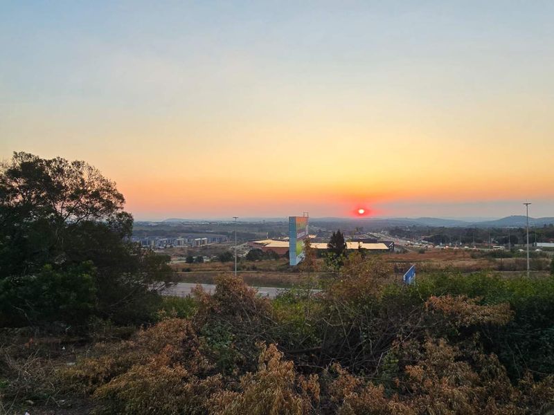 A scenic sunset view overlooking the surrounding landscape and distant urban development from the vacant residential property.