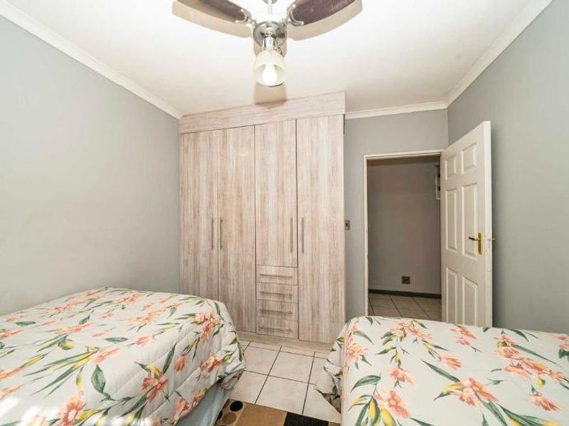 A bedroom featuring built-in wooden wardrobes, a ceiling fan, and tiled flooring.