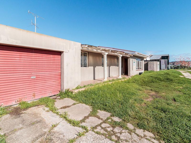 Front exterior view of the house featuring a roller garage door, a covered patio with decorative columns, and a concrete driveway.