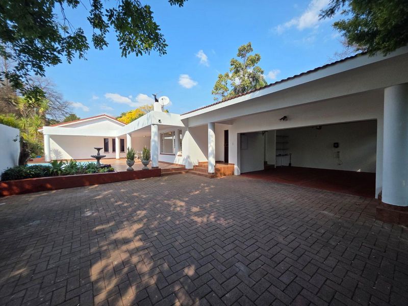 Rear view of the property featuring a paved driveway, covered patio area, swimming pool, and integrated garage.