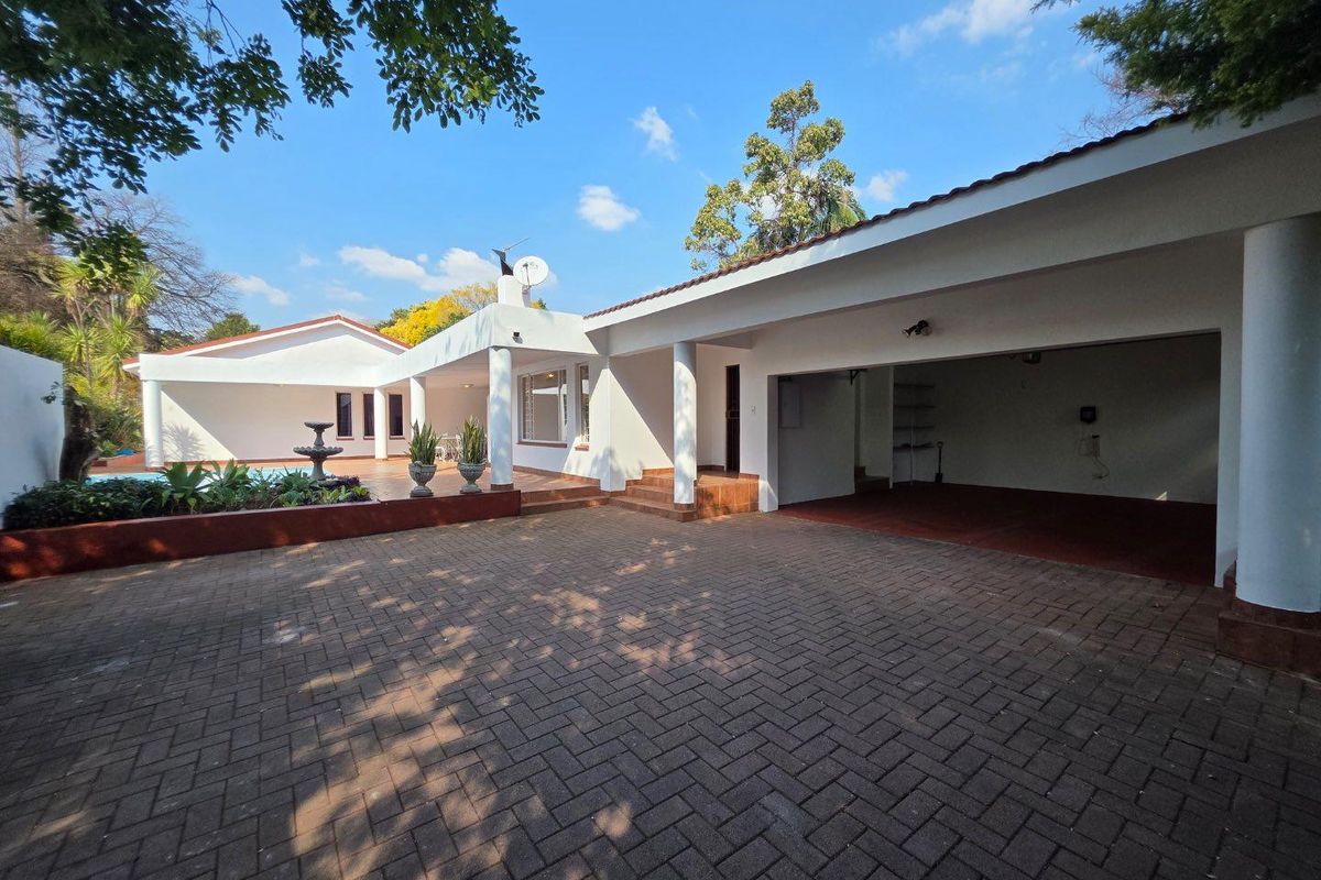 Rear view of the property featuring a paved driveway, covered patio area, swimming pool, and integrated garage.