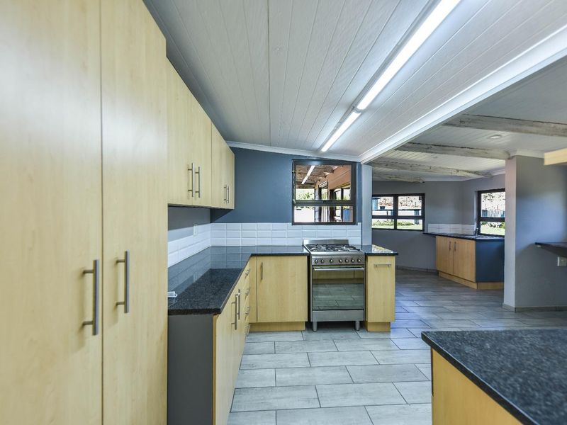 Spacious kitchen featuring light wood cabinetry, granite countertops, gas stove, and tiled flooring, offering a clean and functional layout.