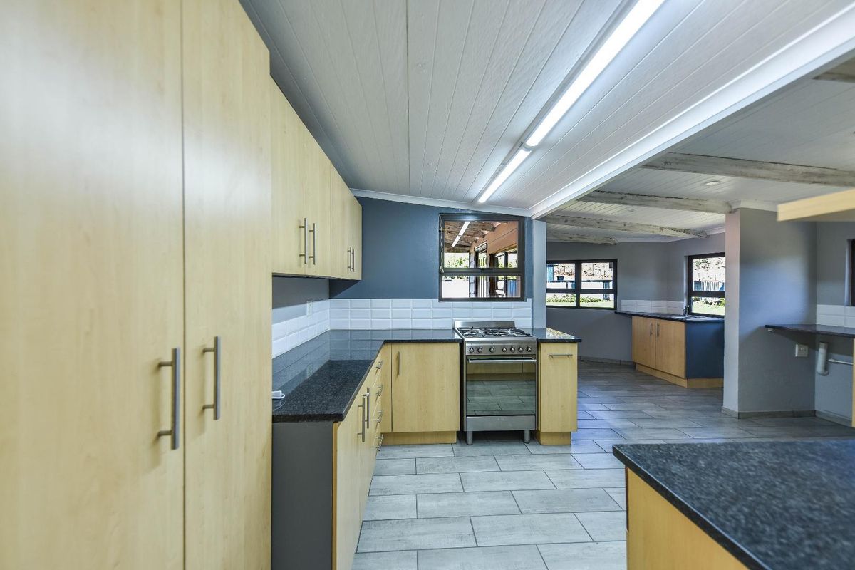 Spacious kitchen featuring light wood cabinetry, granite countertops, gas stove, and tiled flooring, offering a clean and functional layout.