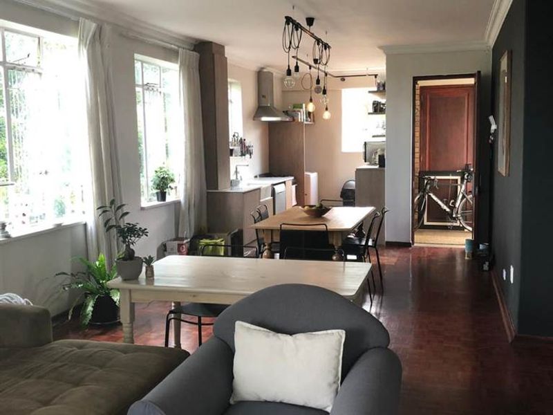 Open-plan living and dining area featuring hardwood flooring, coving, and a functional kitchen space with built-in cabinetry and an extractor fan.