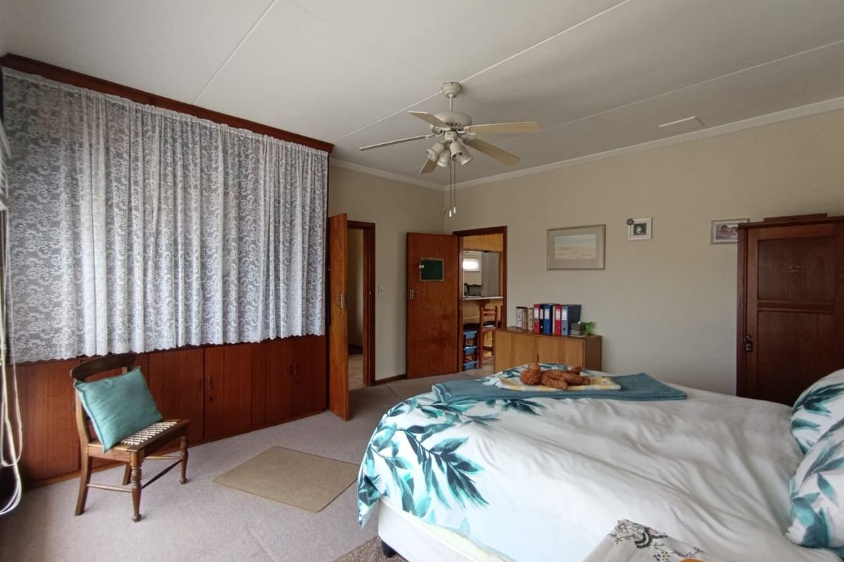 A spacious bedroom featuring built-in wooden cabinetry, a ceiling fan, and neutral wall finishes, offering a comfortable and functional living space.