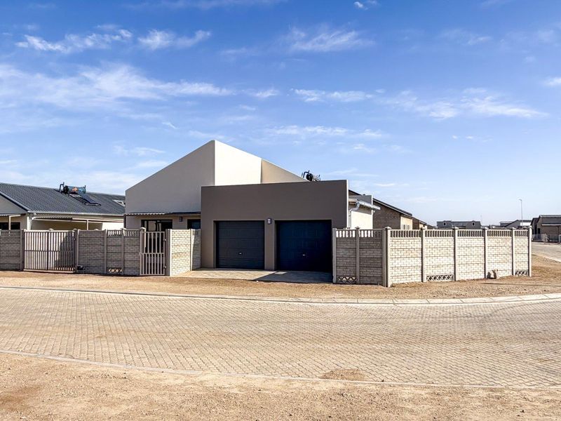 Modern single-story house featuring a double garage, paved driveway, and secure perimeter walling in a quiet residential estate.