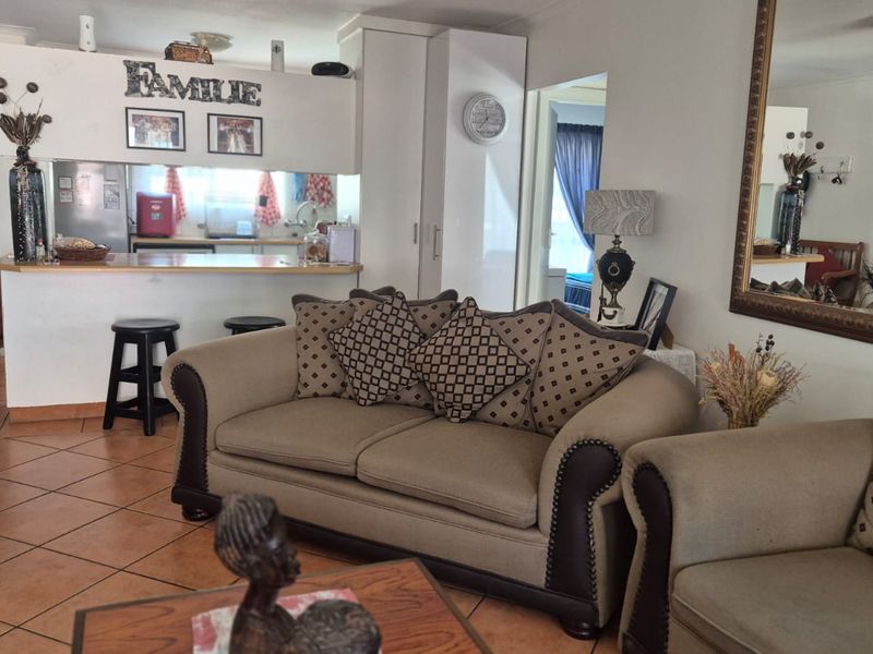 Open-plan living area featuring tiled flooring and a breakfast bar connecting to the kitchen, offering a functional and connected layout.