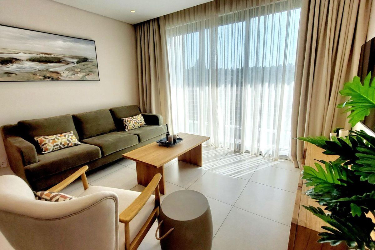 A bright and modern living room featuring large format floor tiles, recessed lighting, and expansive floor-to-ceiling glass doors leading to an outdoor area.
