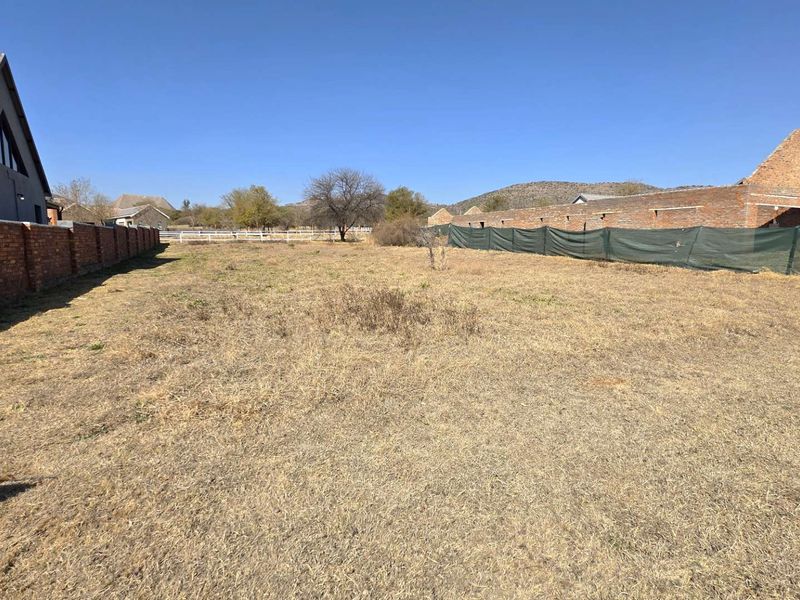 A vacant residential plot featuring established brick boundary walls and temporary shade cloth fencing, offering a clear space for future development.
