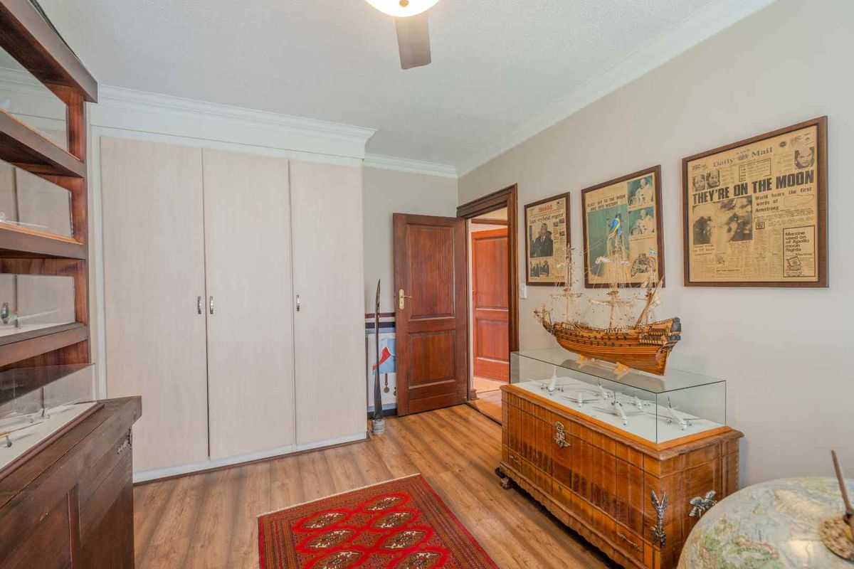 A bedroom featuring built-in wardrobes, wooden flooring, and crown molding, providing a functional and well-maintained living space.