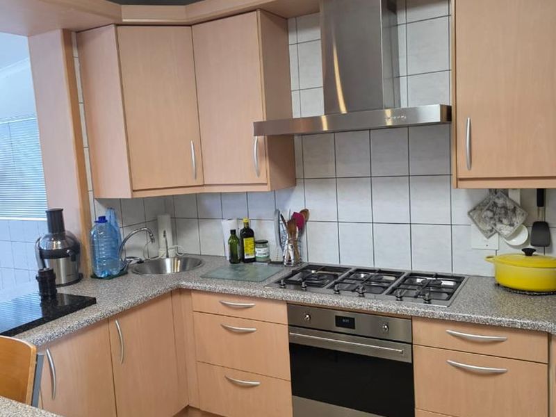 Functional kitchen featuring light wood-tone cabinetry, granite-look laminate countertops, built-in gas hob, stainless steel oven, and extractor fan with tiled backsplash.
