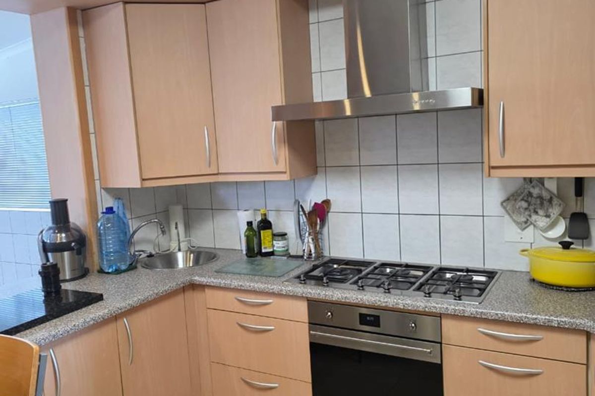 Functional kitchen featuring light wood-tone cabinetry, granite-look laminate countertops, built-in gas hob, stainless steel oven, and extractor fan with tiled backsplash.