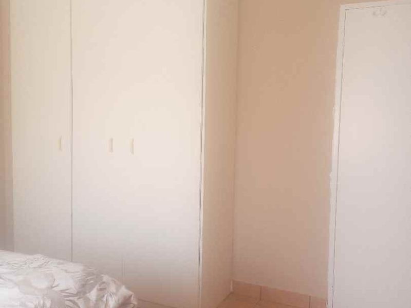 A bedroom featuring built-in cupboards and tiled flooring, offering a neutral canvas for personalization.