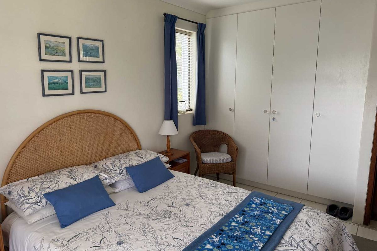 A functional bedroom featuring built-in cupboards, tiled flooring, and a window with natural light.