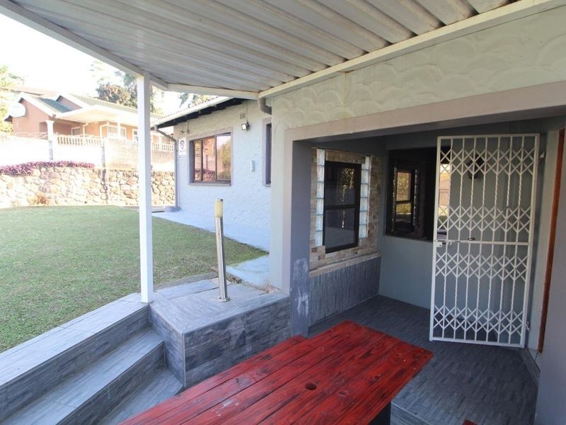 A covered outdoor patio area featuring tiled flooring, a security gate, and direct access to the rear garden space.