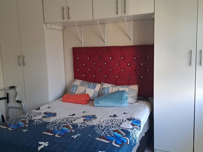A bedroom featuring extensive built-in cabinetry and overhead storage units, providing ample storage space with a functional layout.