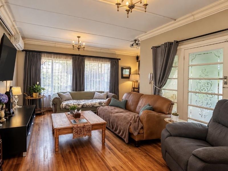 A cozy living room featuring hardwood flooring, a stone veneer accent wall, and glass-paneled french doors leading to the exterior.