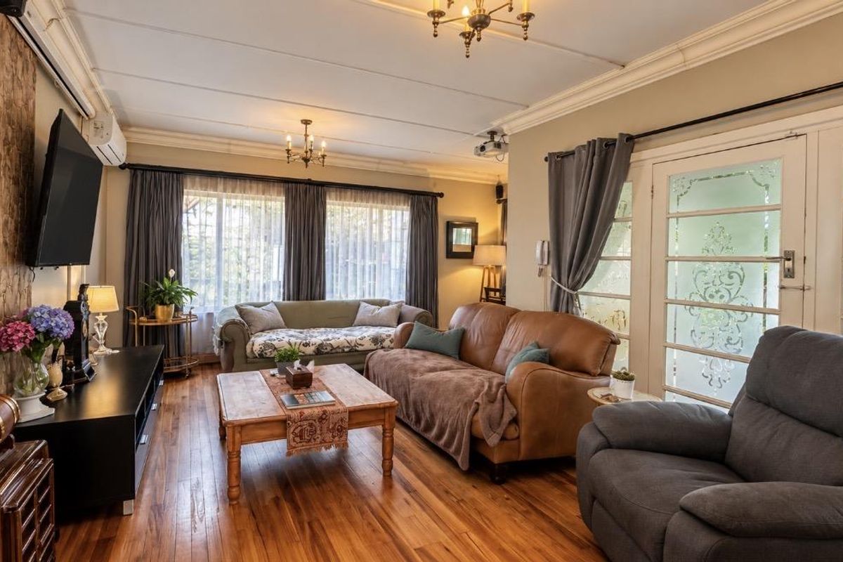 A cozy living room featuring hardwood flooring, a stone veneer accent wall, and glass-paneled french doors leading to the exterior.