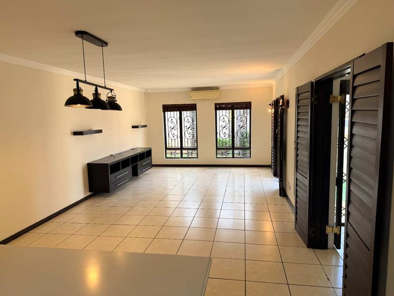 Spacious living area featuring tiled flooring, built-in cabinetry, air conditioning, and decorative pendant lighting, offering a functional and well-lit space.