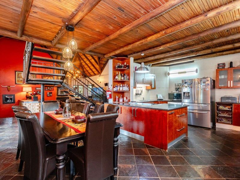 Spacious open-plan living and kitchen area featuring rustic exposed timber ceilings, slate flooring, a central staircase, and a well-appointed kitchen with granite countertops.
