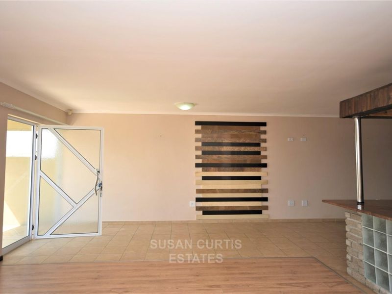 An open-plan living area featuring tiled and laminate flooring, a breakfast bar with glass block accents, and a decorative wall feature.